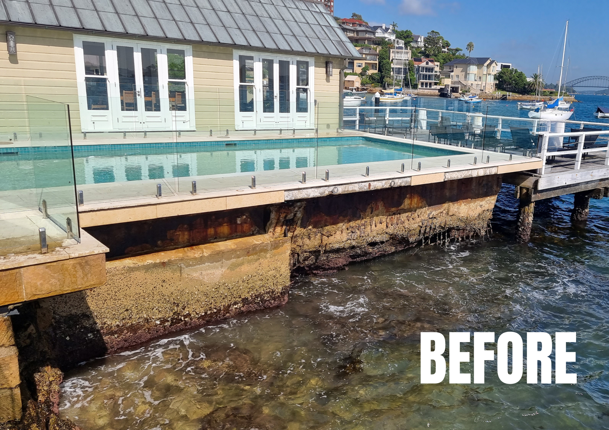 A raised pool over ocean with a rusty yellow wall underneath that's falling apart